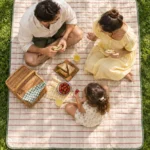 Quiltet picnicmåtte med bærerem på et dækket weekendbord